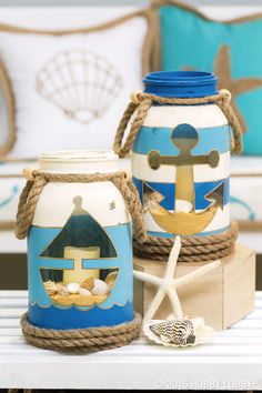 two jars with painted designs on them are sitting on a table next to a starfish and seashell