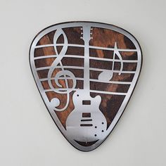 a wooden guitar pick with musical notes on it's side and an electric guitar in the middle