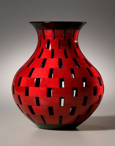 a red and black vase sitting on top of a table