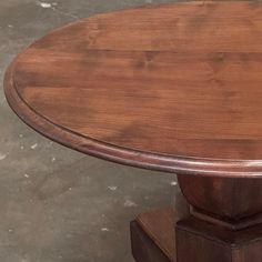 a round wooden table sitting on top of a cement floor