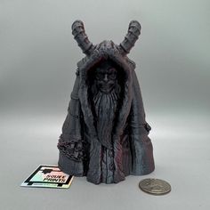 a coin is sitting next to a statue that looks like an old man with horns