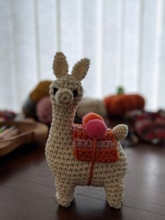 a small crocheted llama with a ball in its mouth on a table