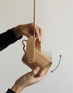 a person holding a wooden cup with a stick in it and an object attached to the handle