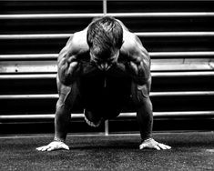 a man is doing push ups on his hands and knees in front of an empty bleachers