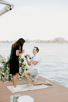 a man kneeling down next to a woman on a dock