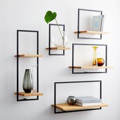 four shelves with vases, books and other items on them against a white wall