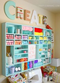 a sewing room with lots of crafting supplies on shelves and letters above the shelf