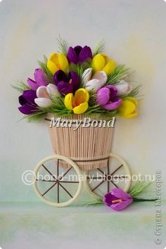 a basket filled with lots of flowers sitting on top of a wooden wheelbarrow