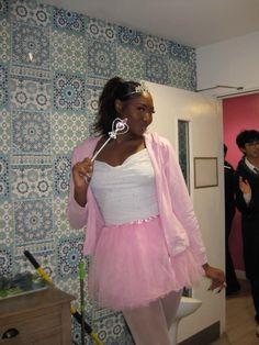 a woman in a pink tutu and white top is holding a pair of scissors