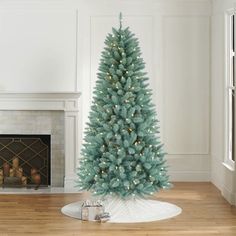 a blue christmas tree sitting on top of a hard wood floor next to a fireplace