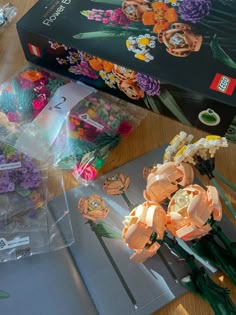 there are many flowers on the table next to some cards and scissors in plastic bags