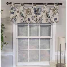 a window with a flowered valance hanging from it's side, next to a lamp