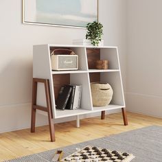 a white shelf with books and baskets on it next to a rug in a room