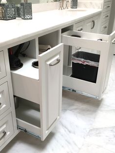 an open cabinet in the middle of a white countertop with drawers and baskets on it