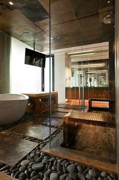 a bath room with a large stone floor and a wooden bench next to a tub