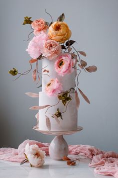 a three tiered white cake with pink flowers on top