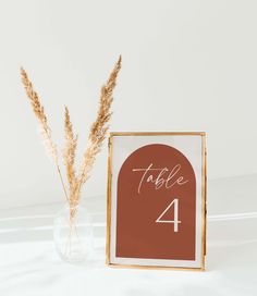 a table number is displayed next to a vase with dried grass in it and a sign that says table 4