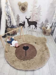 a baby laying on top of a teddy bear rug in a room with deer wallpaper