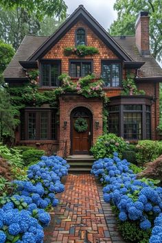 a brick house with blue hydrangeas in the front yard and steps leading up to it