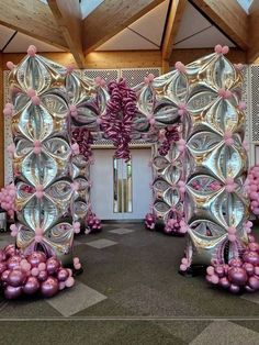 an elaborately decorated entrance to a building with pink and silver balloons on the floor