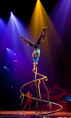 a person is performing on a pole with lights in the back ground and behind her