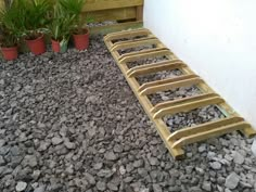 a wooden bench sitting on top of a pile of rocks next to a planter