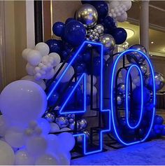 the number forty is lit up with blue and white balloons