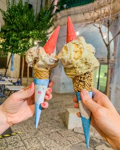 two people holding ice cream cones in their hands