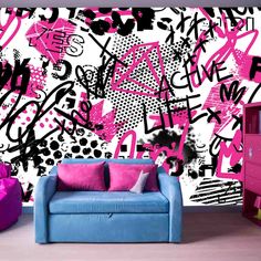 a blue couch sitting in front of a wall covered in pink and black graffiti art