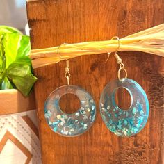 These beautiful blue earrings are inspired by the sea. They are made of blue resin and have blue shell pieces throughout the bottom half. Ocean-inspired Blue Shell Jewelry, Handmade Blue Resin Earrings, Turquoise Dangle Earrings In Resin, Blue Resin Dangle Jewelry, Blue Resin Earrings For The Beach, Blue Resin Earrings For Beach, Handmade Turquoise Resin Earrings, Blue Round Resin Jewelry, Ocean-inspired Blue Earrings For Gifts