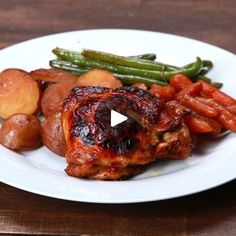 a white plate topped with meat and veggies on top of a wooden table