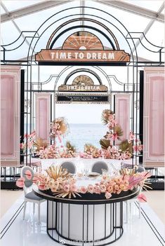 a table with chairs and flowers on it in front of an archway that says time to dream