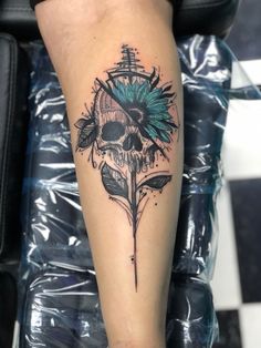 a person with a tattoo on their leg that has a skull and feathers on it