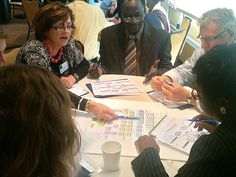 a group of people sitting around a table with papers and pens in front of them