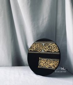 a black and gold plate with arabic writing on the side, sitting against a white background