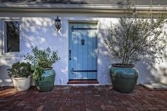 two large planters sitting in front of a blue door on a white stucco house