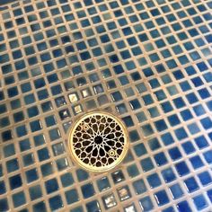 a shower head in the middle of a glass mosaic tile floor with a circular design on it