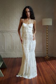 a woman in a white dress standing on a wooden floor with her hands on her hips