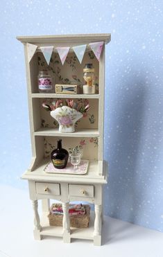 a dollhouse shelf with a vase and other items on it