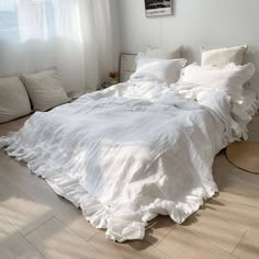 an unmade bed with white sheets and pillows