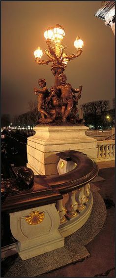 a statue with lights on top of it in the middle of a park at night