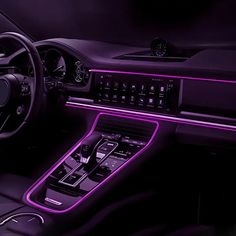 the interior of a modern car with purple lighting and electronic controls on the steering wheel