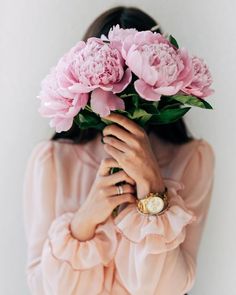 a woman holding pink flowers in her hands