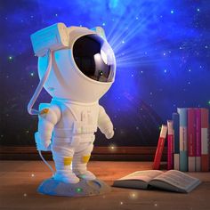 an astronaut statue next to books and a book on a table with fireworks in the background