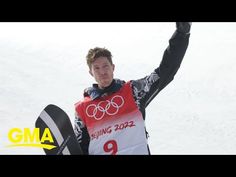 a man is holding his skis in the snow and raising his arms up with both hands