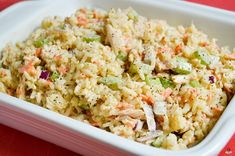 a white bowl filled with rice and veggies on top of a red table cloth