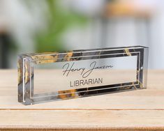 a glass plaque that says happy birthday librarian on it sitting on a wooden table in front of a blurry background