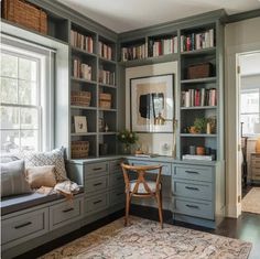 a home office with built - in bookshelves and drawers, along with a window seat