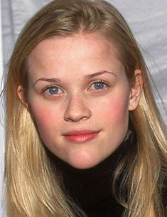 a woman with long blonde hair wearing a black turtle neck sweater and looking at the camera