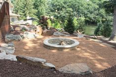 an outdoor fire pit surrounded by rocks and trees